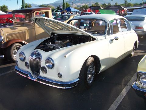 1990 Ford Bronco - A white Jaguar Mark II sedan is displayed with its hood open at a car show.