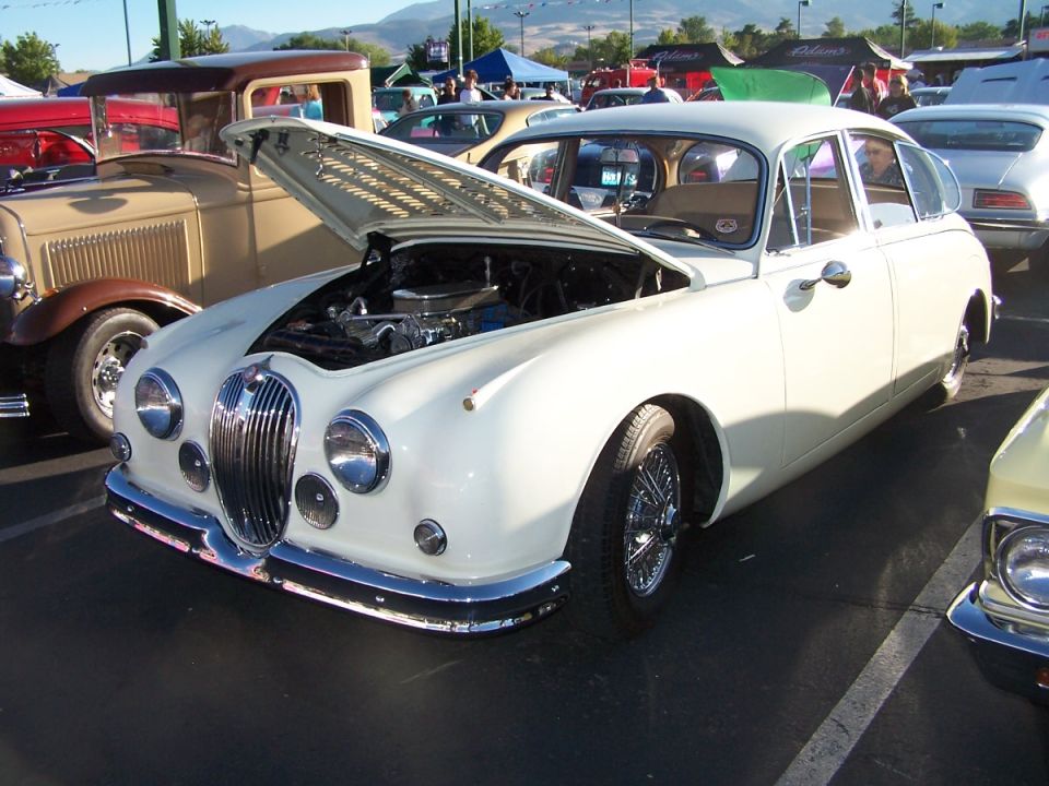 White Jaguar Mark II sedan with hood open, parked at an outdoor car show