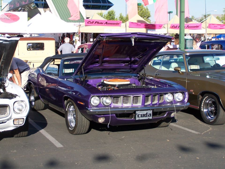 Purple Plymouth Barracuda with hood open, parked next to a brown car. License plate says 'cuda'