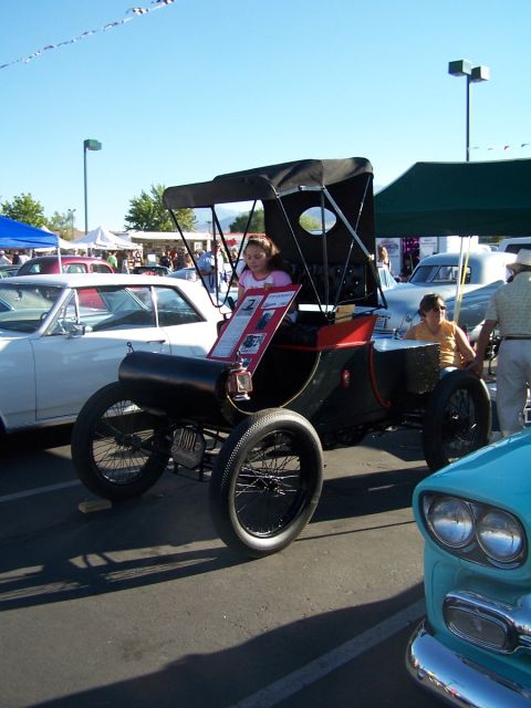 1990 Ford Bronco - An antique car with a black and red body and a canvas top is displayed at an outdoor event.