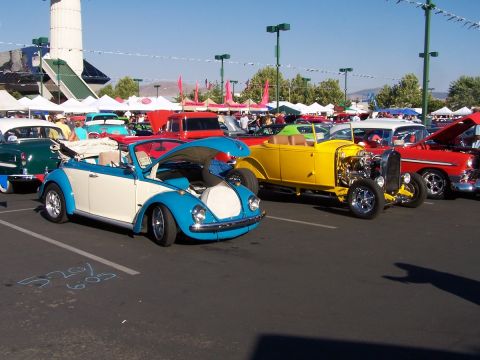 1990 Ford Bronco - A blue and white convertible Volkswagen Beetle is parked at an outdoor car show with its hood open.