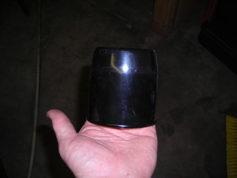 2003 Jeep TJ - A hand holds a black cylindrical object, which appears to be a vehicle part, against a dark background.