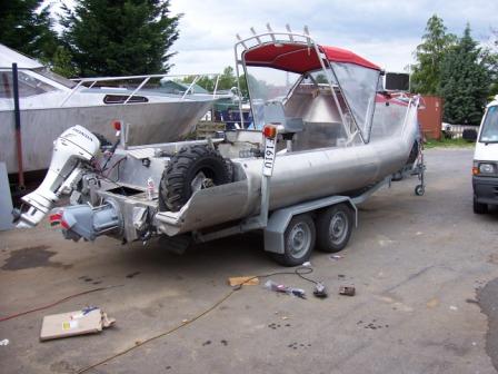 1978 Ford Bronco - A boat on a trailer, equipped with an outboard motor and a spare tire, parked outdoors.