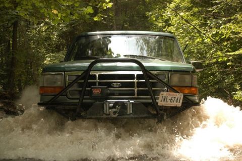 1996 Ford Bronco - 1996 Ford Bronco navigates a water crossing, kicking up spray.