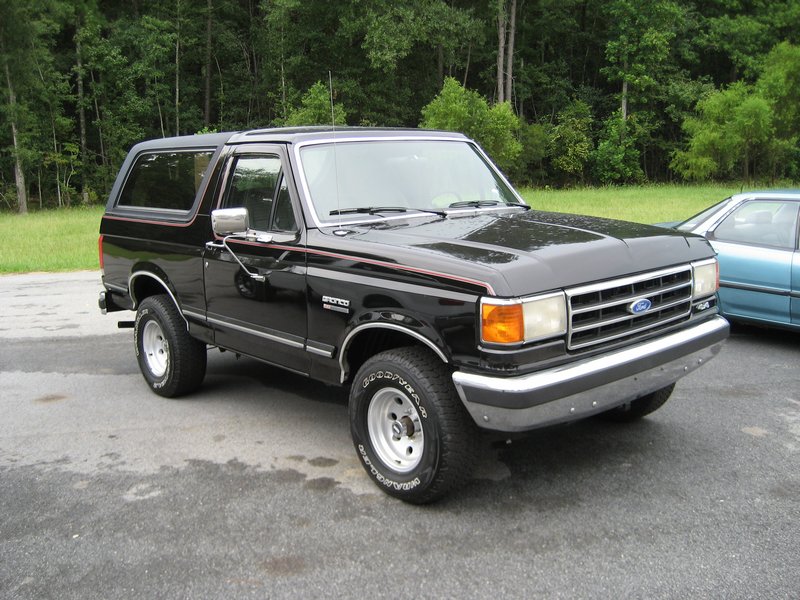 Black two-door Ford Bronco SUV, front three-quarter view, white wheels and chrome bumper