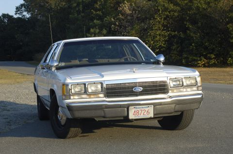 1991 Ford Crown Victoria LTD - This white sedan, likely from the early 1990s, is shown from the front with its grille and headlights clearly visible.