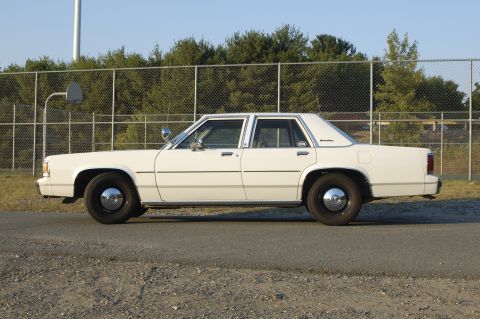 1991 Ford Crown Victoria LTD - Side view of a white sedan with a distinctive 1980s boxy body style.
