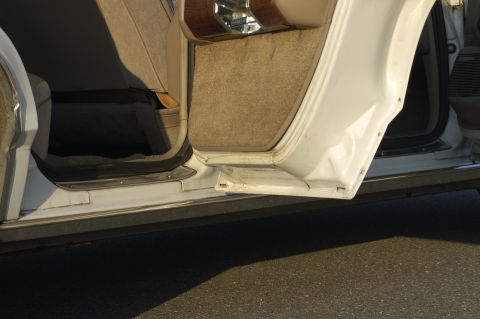 1991 Ford Crown Victoria LTD - Close-up of the interior door frame and carpet of a white vehicle.