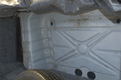 1991 Ford Crown Victoria LTD - The trunk interior of a 1991 Ford Crown Victoria LTD shows a spare tire and the white metal floor with a ribbed pattern.