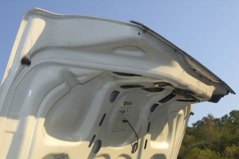 1991 Ford Crown Victoria LTD - The underside of a white hood is visible against a clear blue sky, showing a sticker with text.