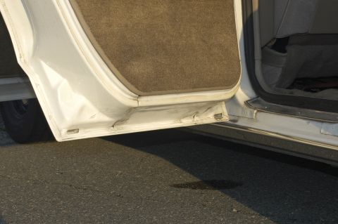 1991 Ford Crown Victoria LTD - Close-up of a damaged car door sill with interior carpet visible.