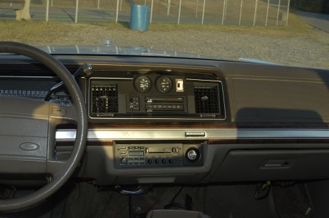 1991 Ford Crown Victoria LTD - The interior dashboard of a 1991 Ford Crown Victoria LTD features wood grain trim, dual gauges, and an aftermarket cassette player.
