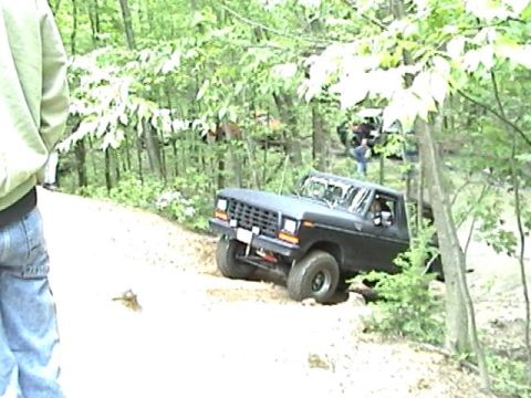1978 Ford Bronco - A black 1978 Ford Bronco navigates a wooded trail with other vehicles visible in the background.