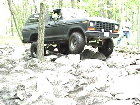 1978 Ford Bronco - A 1978 Ford Bronco navigates a rocky trail in a forest.