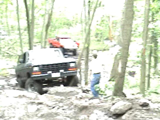 1978 Ford Bronco front view off-roading in woods with another vehicle behind