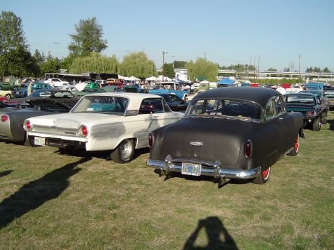1964 Ford Fairlane - Two classic American sedans, a 1954 Chevrolet and a 1964 Ford Fairlane, at an outdoor car show.
