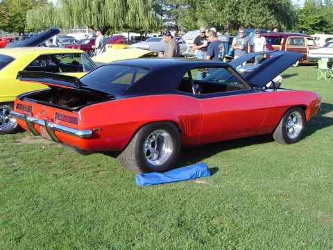 1964 Ford Fairlane - A red and black 1969 Chevrolet Camaro is displayed at an outdoor car show.