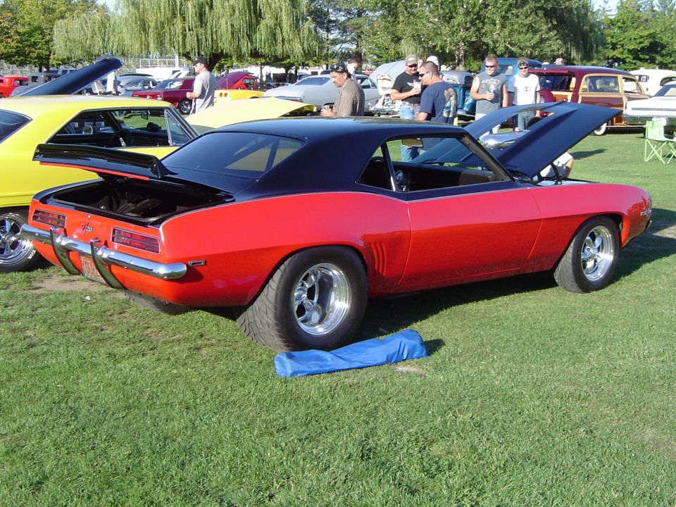 Red and black 1969 Chevrolet Camaro with hood and trunk open, parked on grass