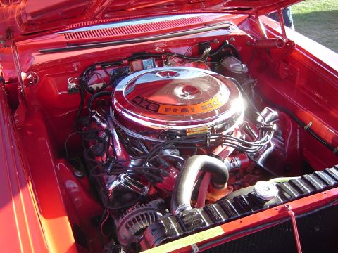 1964 Ford Fairlane - The engine bay of a red car features a prominent 426 Hemi engine with a chrome air cleaner and orange accents.