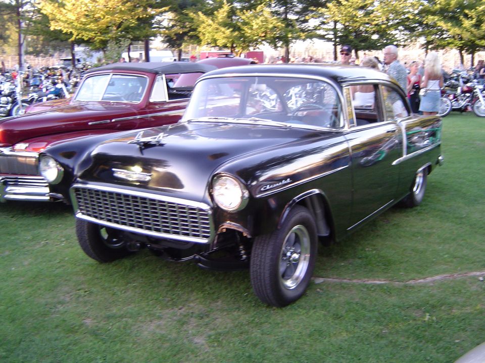 Black 1955 Chevrolet sedan with chrome grille and trim, parked on grass