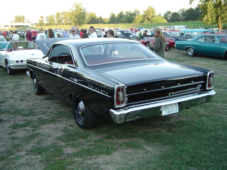 Black Ford Fairlane hardtop, rear 3/4 view with red interior and dog-dish hubcaps