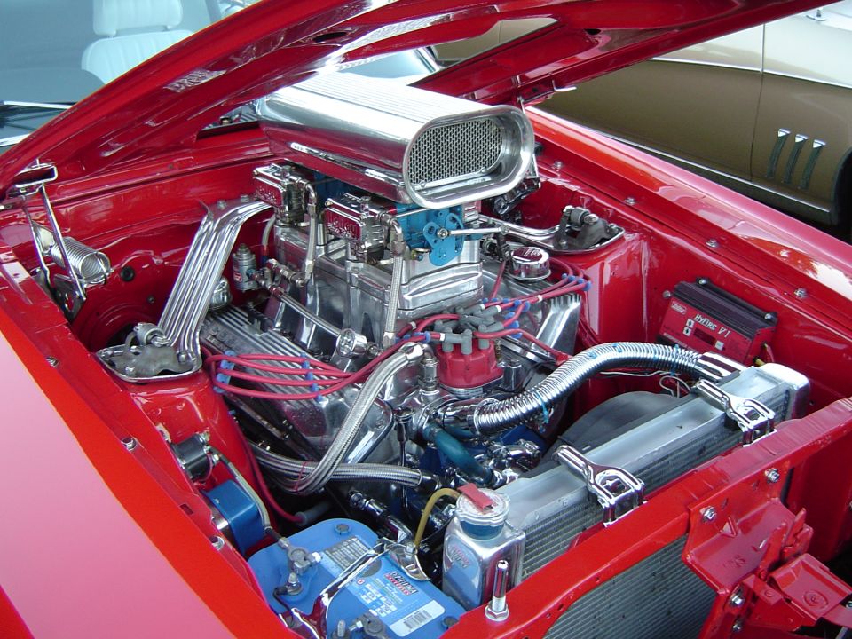 Red engine bay with chrome air intake and blue battery