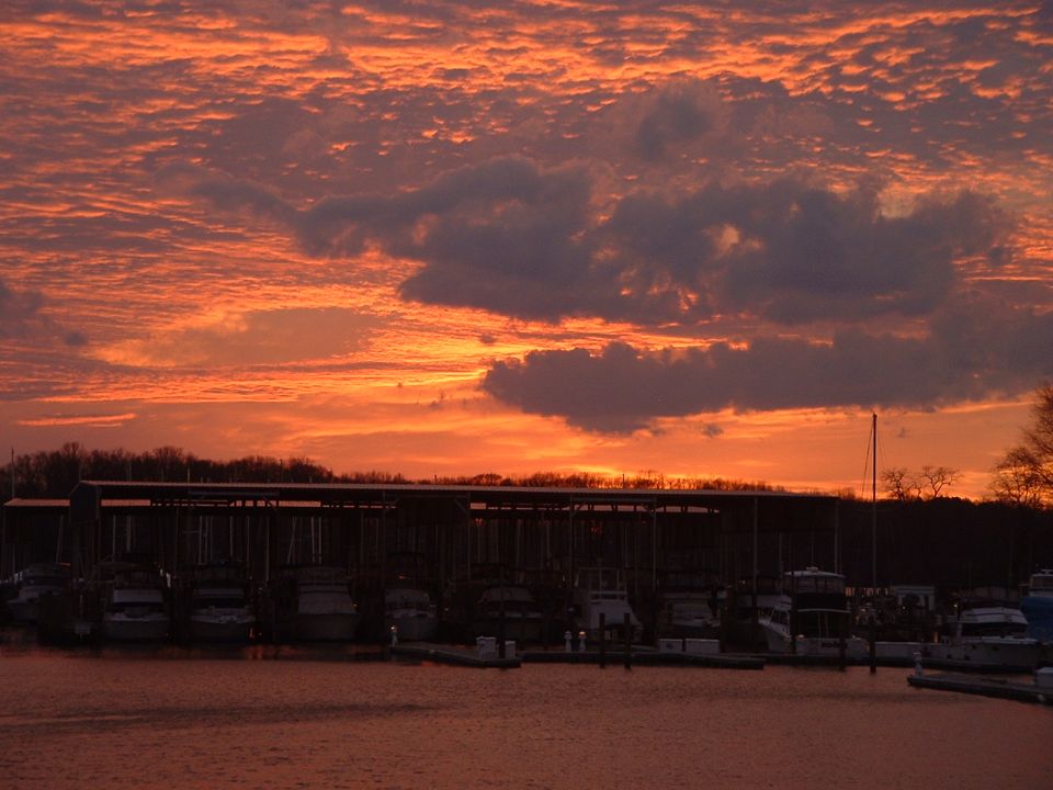 Boats docked at a marina with a colorful sunset sky overhead