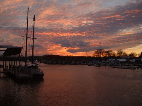 1994 Ford Bronco - A sailboat is docked at a marina during a vibrant sunset, with other boats visible in the distance.