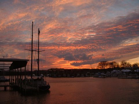 1994 Ford Bronco - A sailboat is docked at a marina during a vibrant sunset with orange and pink clouds.