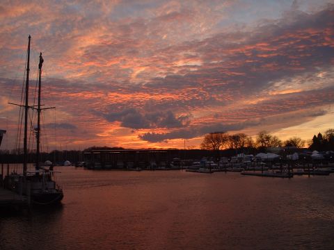 1994 Ford Bronco - A sailboat is docked at a marina during a vibrant sunset with colorful clouds over the water.