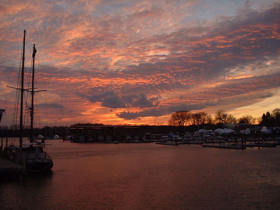 Marina scene at sunset with sailboat and boats docked