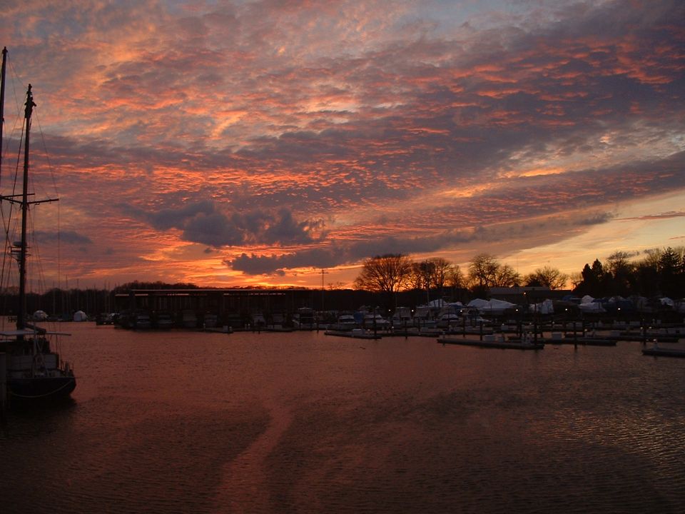 Marina with boats docked at sunset, colorful clouds overhead