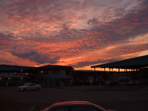 1994 Ford Bronco - The sky is ablaze with color during a sunset, casting a warm glow over a waterfront area with buildings and docked boats.