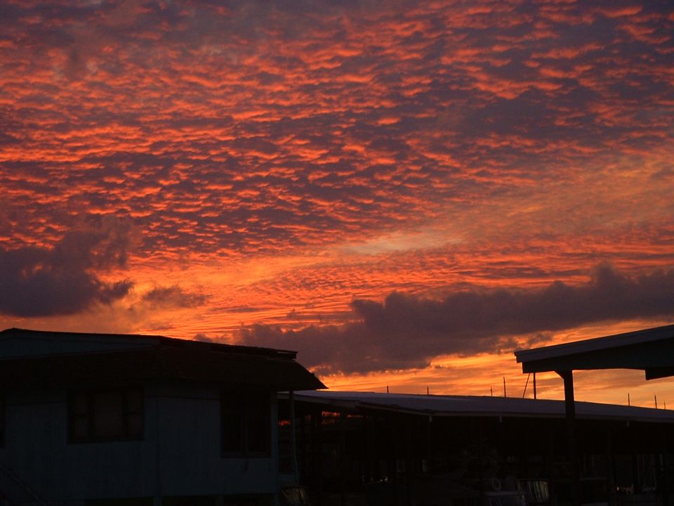 Sunset sky with orange and red clouds over silhouetted buildings and a Supermotors.net watermark
