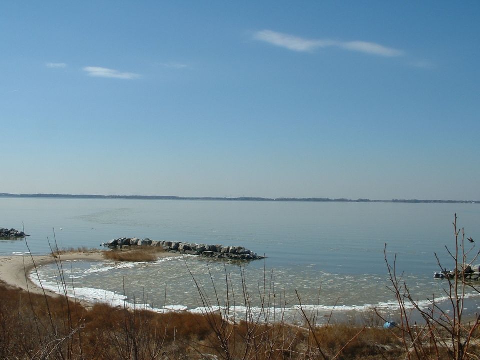 calm lake with a rocky shoreline and dry grass under a clear blue sky
