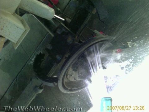 1987 Suzuki Samurai - Water sprays onto a vehicle's brake assembly, obscuring the view of the part.