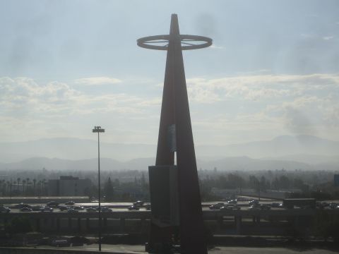 1990 Ford Bronco - tall slender steel tower topped with a ring stands against a hazy sky above a parking lot and distant mountains.