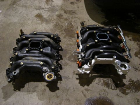 2000 Ford Crown Victoria - Two intake manifolds are shown side-by-side on a concrete surface.