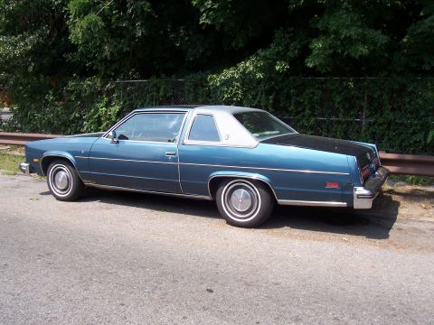 1999 Ford Crown Victoria - This two-door coupe features a blue body with a contrasting silver roof and is seen from its side profile.