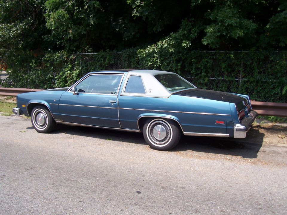 Blue two-door coupe with silver roof parked on roadside
