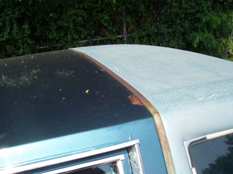 1999 Ford Crown Victoria - Detail of a car's roof showing two-tone paint and rust on the trim piece separating the sections.