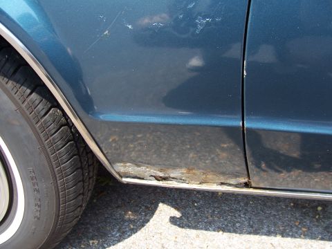 1999 Ford Crown Victoria - The lower section of the car door exhibits extensive rust and corrosion, indicating potential structural compromise.