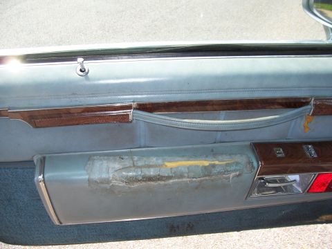 1999 Ford Crown Victoria - Interior door panel shows significant wear and tear on the armrest area.