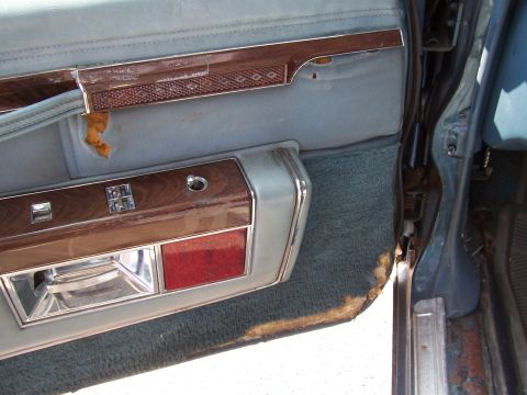1999 Ford Crown Victoria - The interior door panel shows signs of wear and tear, with peeling fabric and faded trim.