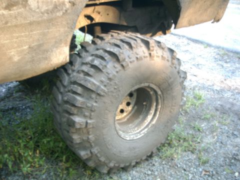 1991 Chevrolet Suburban - A close-up view of a heavily used off-road tire on a vehicle, with mud splattered on the fender and tire.