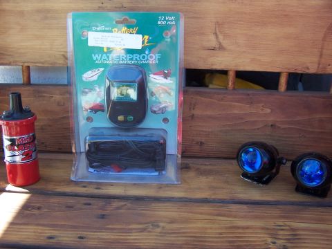 1994 Ford Probe - Collection of automotive parts, including an MSD ignition coil, a Deltran waterproof battery charger, and a pair of blue fog lights, displa…