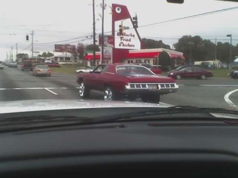 1979 Ford F-150 - Red sedan with chrome trim drives down a street with a Kentucky Fried Chicken in the background.