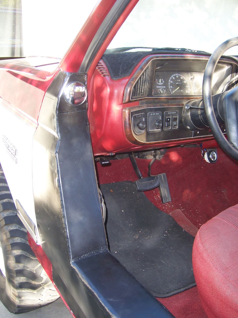 1991 Ford Bronco interior with red dashboard and seats, showing pedals and instrument cluster