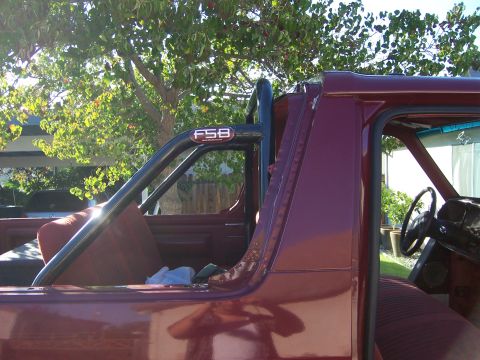 1991 Ford Bronco - The interior of a maroon 1991 Ford Bronco is visible, a black roll bar with 'FSB' branding.
