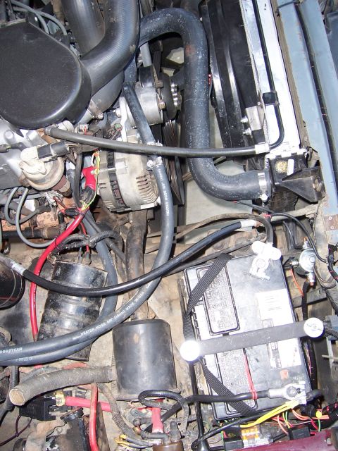 1991 Ford Bronco - Close-up of an engine bay, the battery, radiator hoses, and alternator.